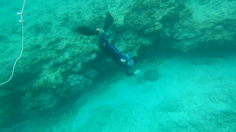 沖縄塩川ビーチの海に潜るインストラクターの男性